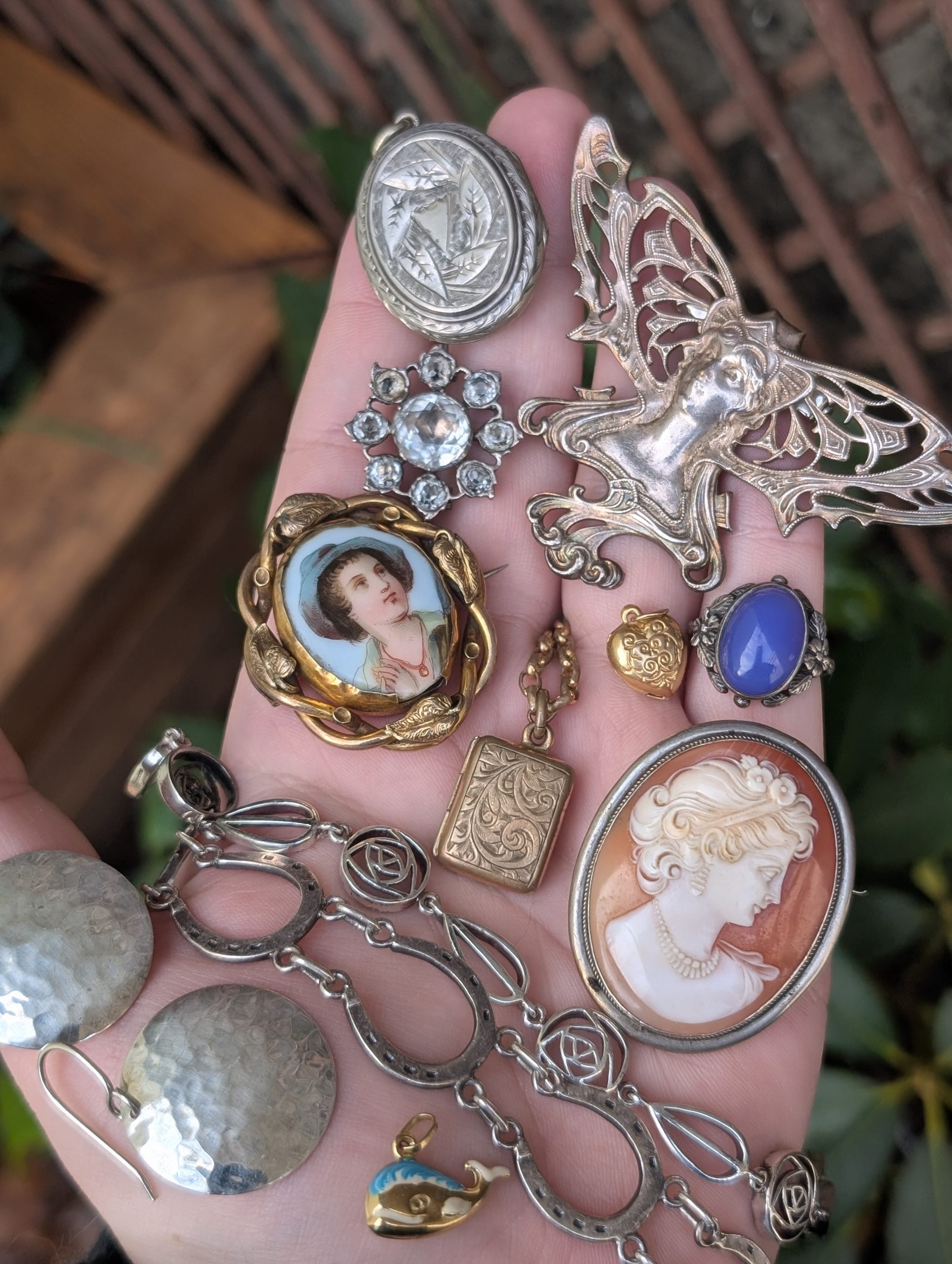 Collection of vintage jewellery pieces including brooch, necklaces and earrings on a hand for display purposes.